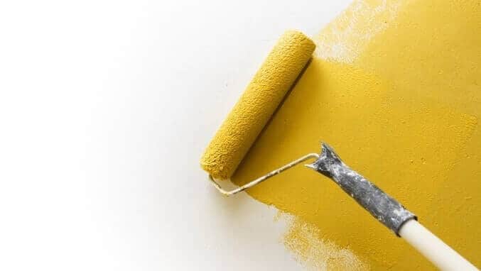 Paint roller applying paint on white wall, home improvements