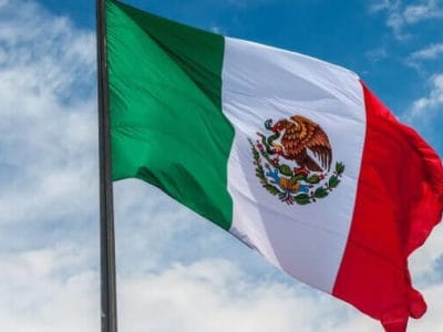 Flag of Mexico over blue cloudy sky