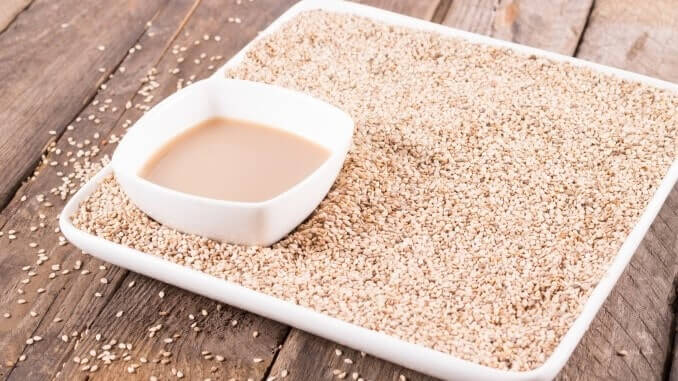 Tahini, sesame paste, on a rustic background. Tinting. Healthy food and drink