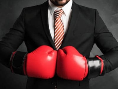 Mann im Anzug mit Boxhandschuhen – der Kampf um die Produktbezeichnun Fleisch für Fleischalternativen