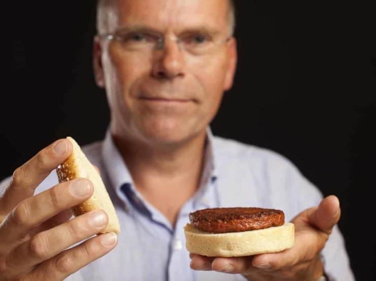 Meat, hält Hamburger aus kultiviertem Fleisch in die Kamera